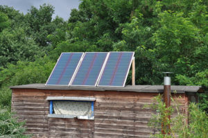 Ein Off grid Holzhaus mit Solarmodulen im Wald.